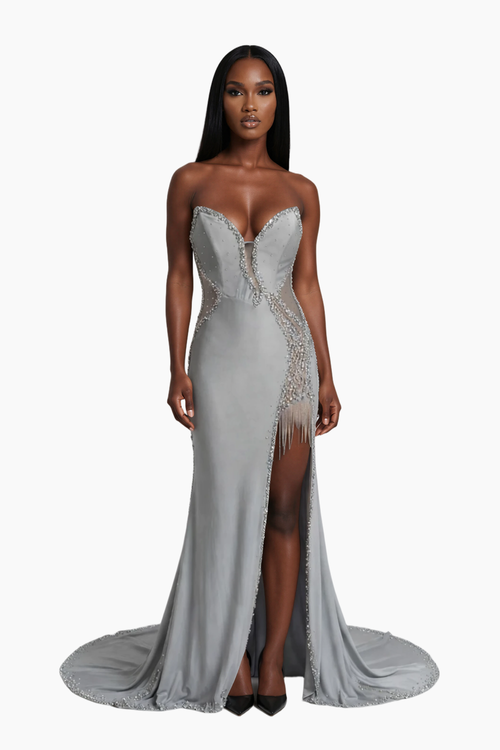 Woman wearing a silver evening gown with intricate detailing on a white background