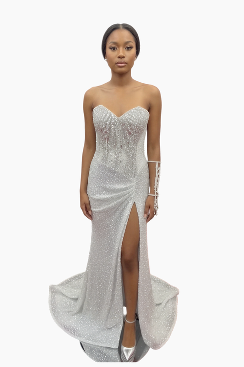 Woman wearing a silver strapless gown with a high slit on a white background