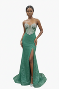 Woman wearing a green evening gown with a high slit on a white background