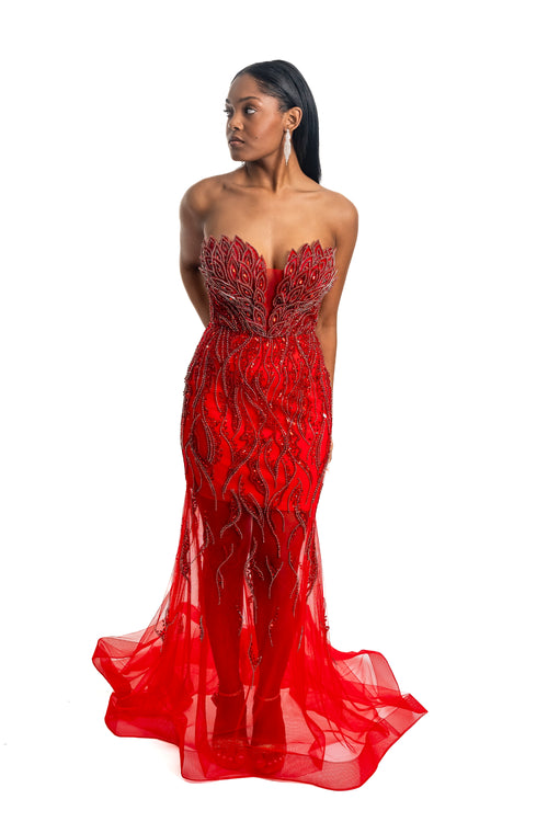 Woman wearing a red strapless gown with intricate detailing on a white background