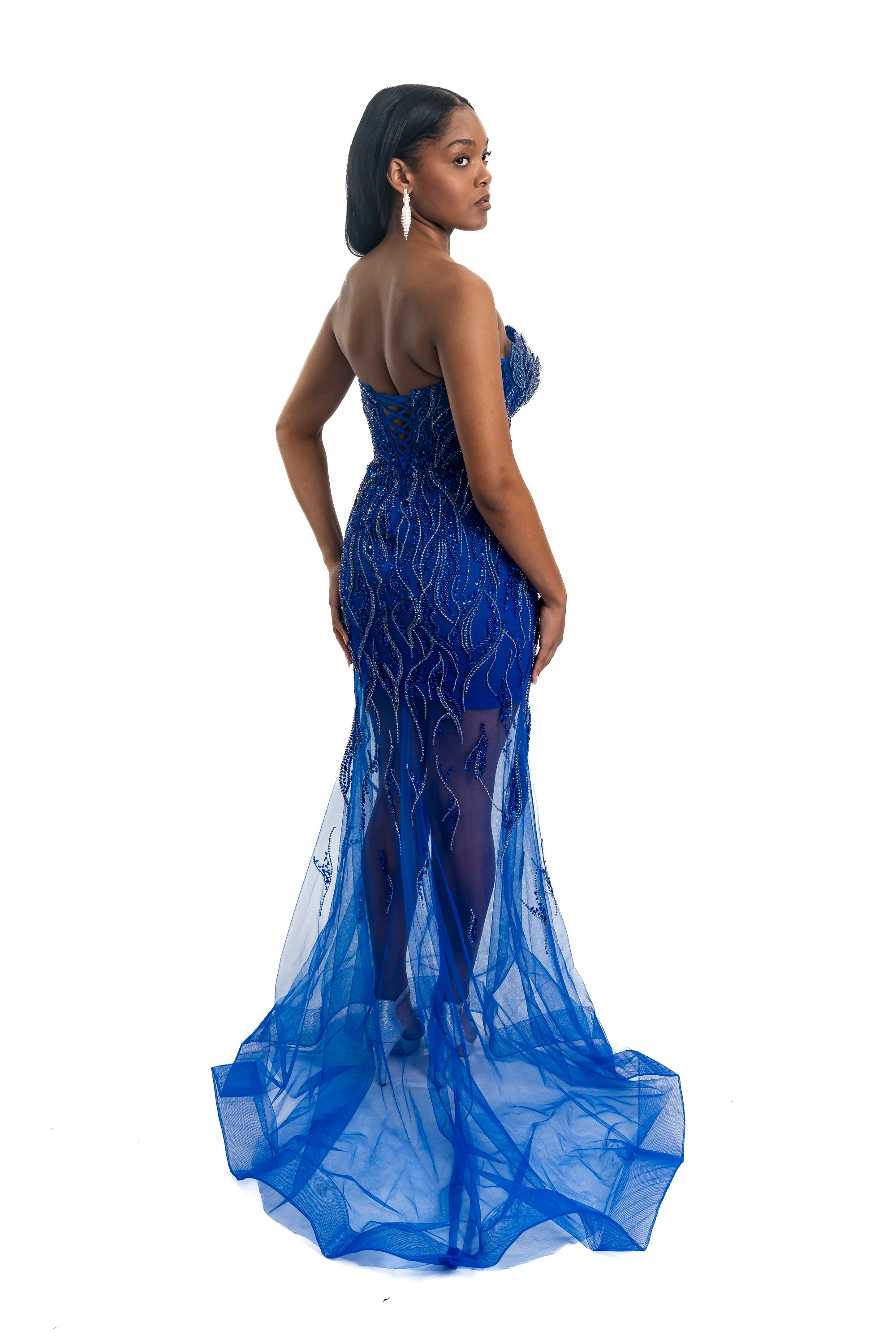 Woman wearing a blue strapless gown with intricate detailing on a white background